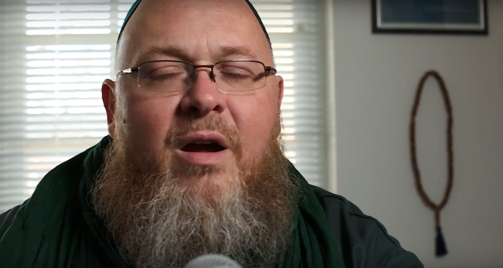 Closeup of Shane Atkinson, eyes closed, singing
