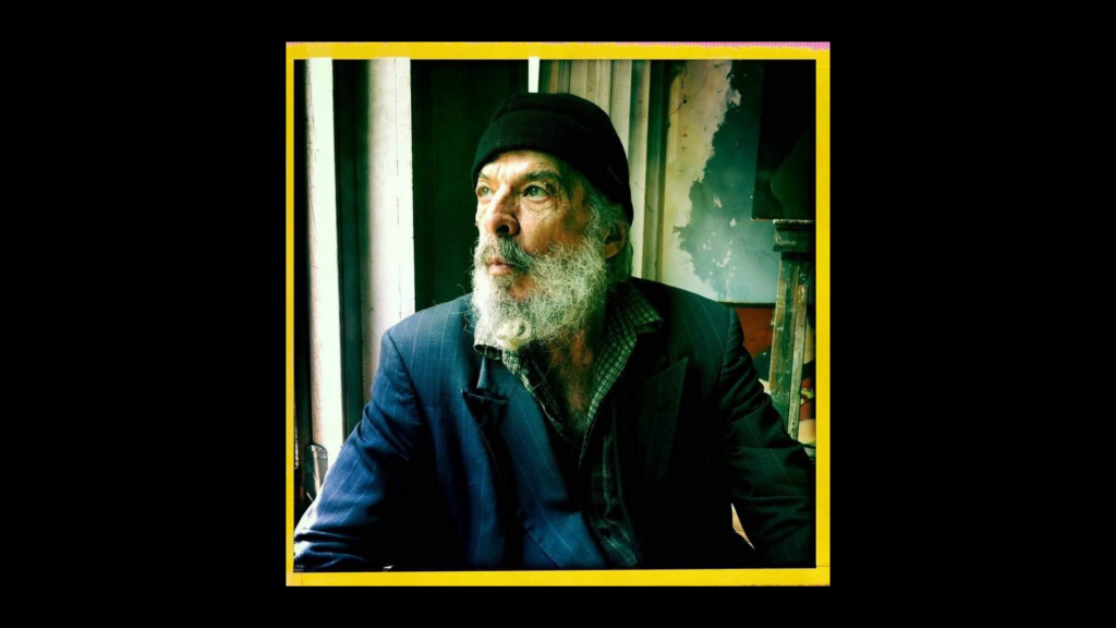 Portrait of George Dureau with white beard in studio, looking out window