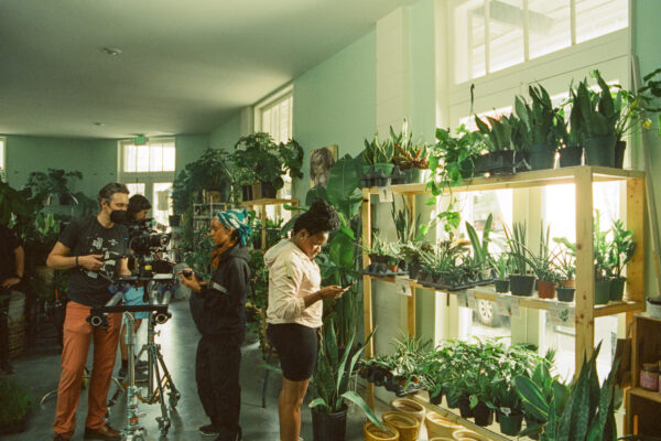 Behind the scenes with camera, cast, and crew inside plant shop