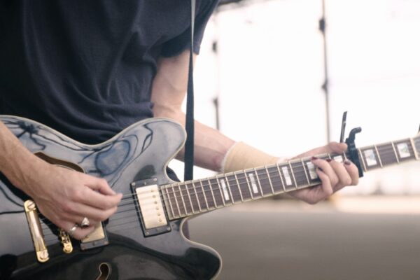 Closeup of bass guitar being played outdoors