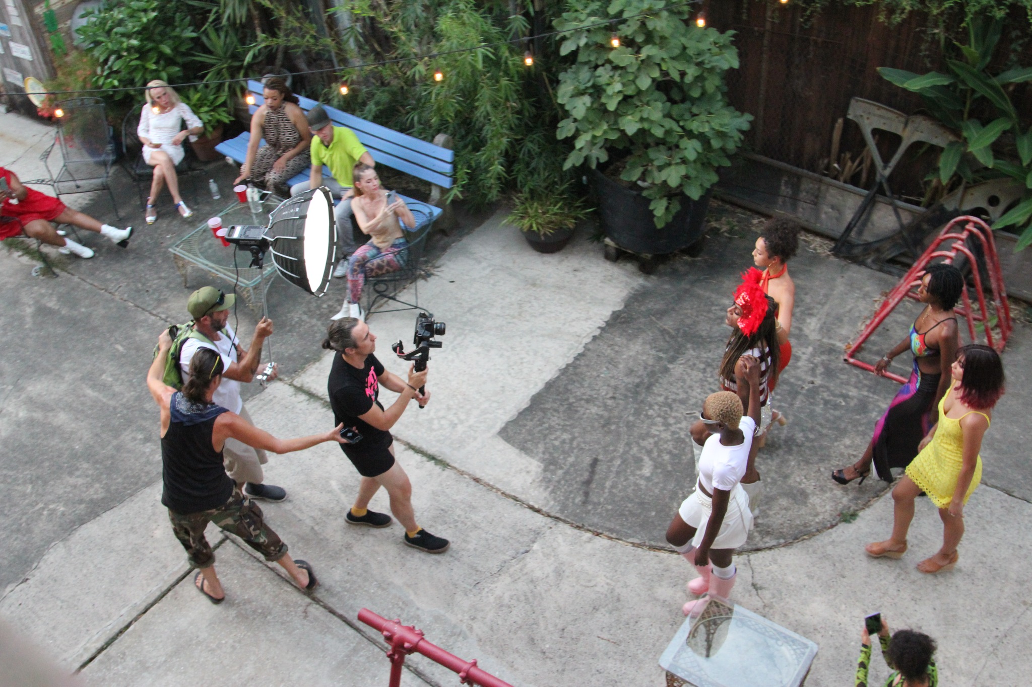 High angle photo of camera person walking backwards with tech time while filming five people walking in formation for fashion shoot