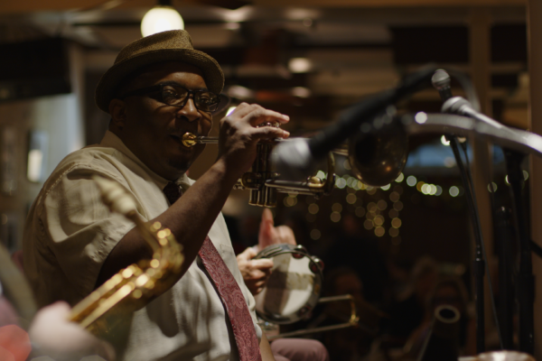 Man plays trumpet on stage in darkened jazz club